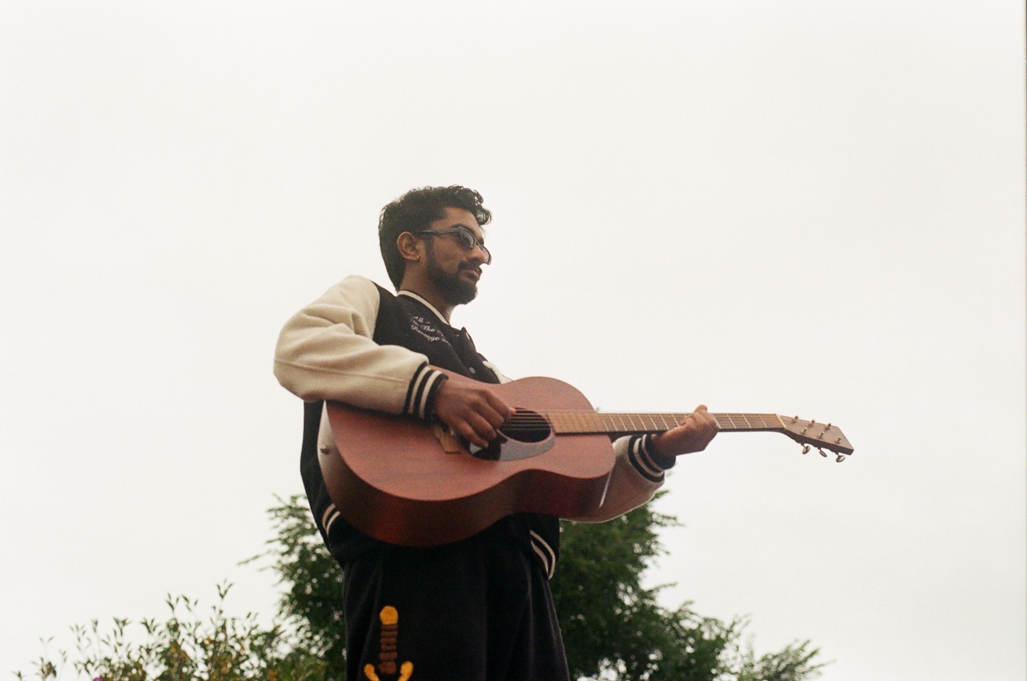 paul injeti playing an acoustic guitar against a white sky